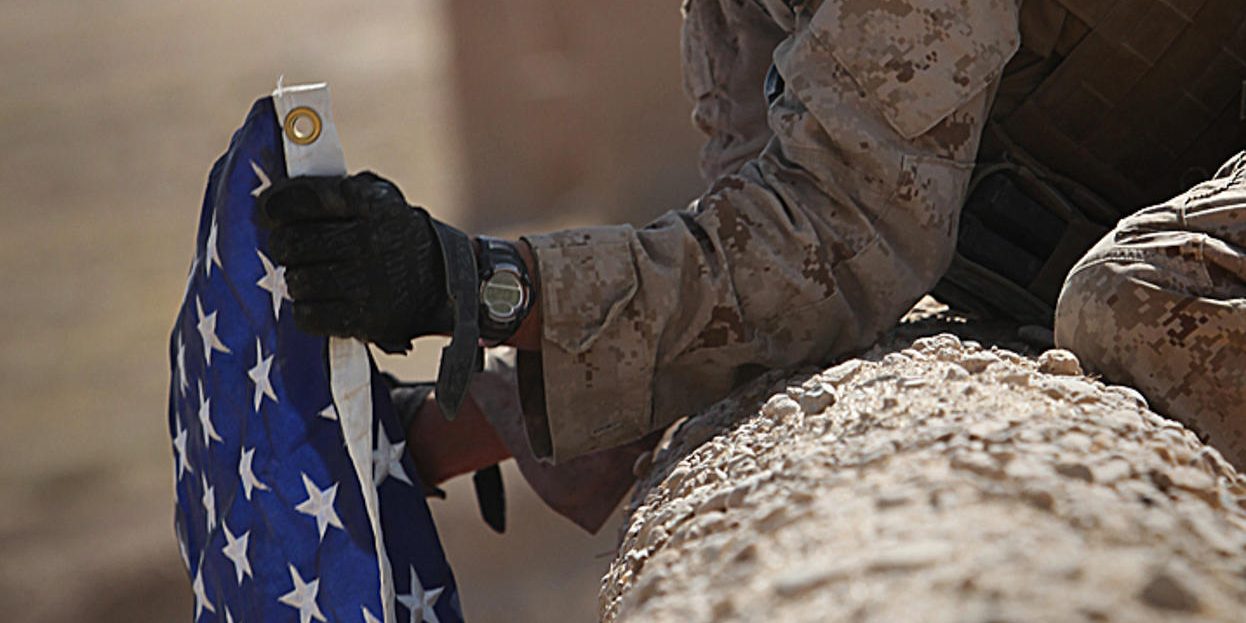 U.S. Marine Corps Cpl. Jorge Villarreal, a motor transportation mechanic with India Battery, 3rd Battalion, 12th Marine Regiment, Regimental Combat Team 2, displays a U.S. flag atop the wall of a compound Sept. 29, 2010, in Kajaki district, Helmand provin